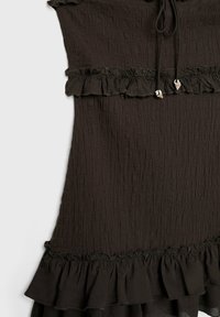 Robe noire texturée avec des volants en étages et une taille à cordon ornée de perles en forme de coquillage.