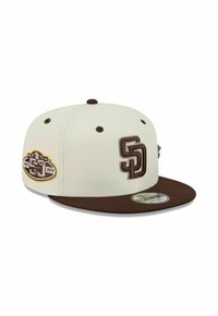 Casquette snapback beige et marron avec le logo "SD" à l'avant et un patch 1983-2019 sur le côté, visière plate et oeillets de ventilation.
