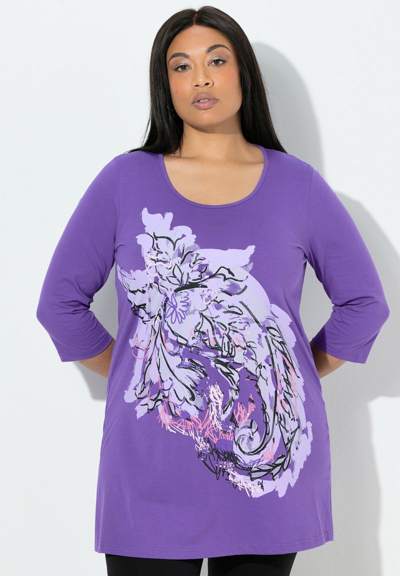 Fioletowa tunika z rękawami do łokcia, z dużym kwiatowym wzorem w czerni i jasnym fiolecie na przodzie. Miękka tkanina z dekoltem w kształcie litery U.