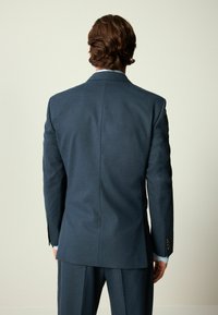 Marineblauer Anzug mit taillierter Passform, flachen Revers und drei Knöpfen. Verfügt über vertikale Textur und goldene Knopfakzente an den Manschetten.