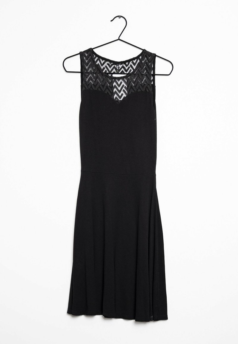 Robe noire avec un corsage ajusté et une jupe évasée. Présente un haut en dentelle texturée avec des motifs en zigzag. Accrochée à un cintre noir.