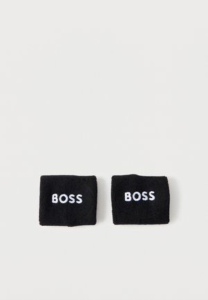 Paire de bracelets en éponge noire avec le texte "BOSS" brodé en blanc sur chacun, présentée sur un fond clair uni.