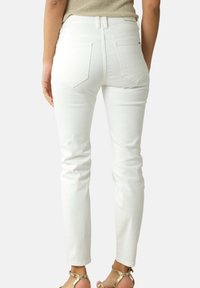 Jean en denim blanc au design ajusté, avec quatre poches et une taille mi-haute. Texture lisse et subtil détail de couture.
