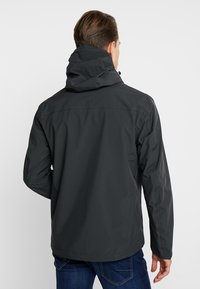 Mørkegrå vandtæt jakke med hætte, der har en glat stoftekstur og tætsiddende design, med sømme og lige snit i bunden.