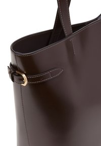 Sac fourre-tout en cuir brun foncé avec une texture lisse, doté d'un accent boucle et de coutures apparentes le long des coutures. Conception à ouverture supérieure.