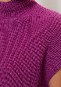 Dzianinowy top z wysokim kołnierzem w intensywnym kolorze magenta z fakturowanym wzorem. Posiada krótkie rękawy i luźny krój.