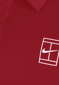 Rød polo T-shirt med et struktureret stof, der har et hvidt Nike-logo og et geometrisk designelement på venstre side.