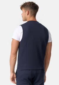Chaleco sin mangas de color Navy, confeccionado en material suave, con un diseño ajustado, que presenta una espalda lisa con detalles de costura sutiles y aberturas laterales.