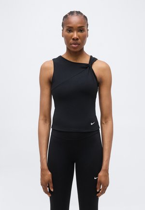 Αθλητική γυναίκα με πλεξούδες, που φοράει μαύρο αμάνικο τοπ με λεπτομέρεια κόμπου και αντίστοιχο μαύρο κολάν με λευκά λογότυπα Nike.