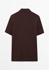 Hnědá polo košile vyrobená z hladké látky, s klasickým límečkem a krátkým rukávem. Jednoduchý, nezdobený design bez viditelných log. 