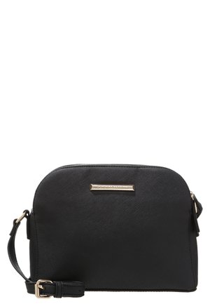 Sort læder crossbody taske med guldspænde og lille guldfarvet rektangulært mærke foran, mod hvid baggrund.