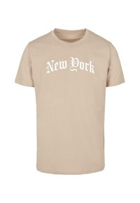 Beige pamut póló kerek nyakkal. Az elején fehér, ívelt betűkkel dekoratív betűtípussal írt "New York" felirat található. Rövid ujjú.