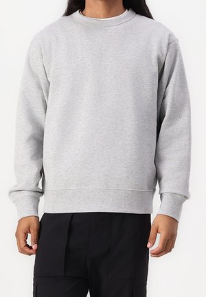 Grijze sweatshirt met een ronde hals, lange mouwen en ribgebreide manchetten, gemaakt van een soepele katoenmix. Gecombineerd met zwarte broek.