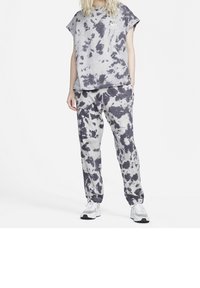 Harmaa batik-kuvioitu T-paita, jossa on lyhyet hihat, yhdistettynä samansävyisiin collegehousuihin. Molemmissa on rento istuvuus ja pehmeä materiaali. Mukana valkoiset tennarit.