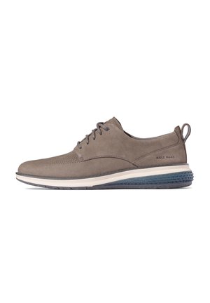 Graue Wildleder-Sneaker mit Perforierungen, Schnürdesign und einer weißen Mittelsohle. Strukturierte dunkelblaue Gummiaußensohle und Zuglasche an der Ferse.