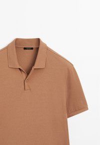 Short-sleeve camel brown polo shirt with two-button placket and ribbed collar on a white background.