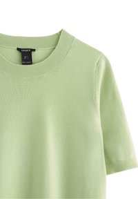 Maglione verde chiaro a maniche corte con scollatura rotonda. Realizzato in materiale morbido, presenta polsini e orlo a costine. Etichetta visibile all'interno della scollatura.