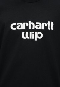 Μαύρο ύφασμα με λευκό λογότυπο κειμένου "carhartt wip" σε παραμορφωμένη, μπλοκ γραμματοσειρά στο κέντρο της επιφάνειας.