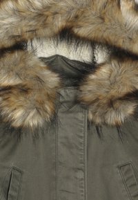 Zielony zimowy płaszcz z beżowym i czarnym sztucznym futrem wokół kaptura oraz dwiema kieszeniami z klapkami z przodu.