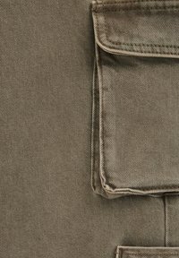 Platnena tkanina maslinasto zelene boje s dijagonalnim tkanjem, s džepom za zakrpe na gornjem desnom dijelu i čistim, ušivenim rubovima.