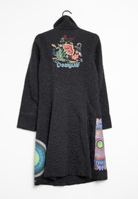 Cappotto nero testurizzato con ricami floreali colorati e logo sulla parte superiore della schiena, e motivi circolari multicolori sull'orlo inferiore.