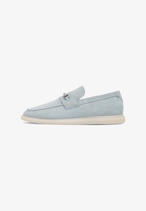 Light blue suede shoes with a slip-on design, featuring a decorative strap and subtle stitching accents. Cream rubber sole for comfort.