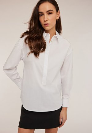 Witte langemouwen shirt met een knoopsluiting en kraag, gemaakt van gladde stof, gecombineerd met een aansluitende zwarte rok.