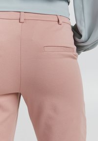 Svetle růžové kalhoty s texturovanou tkaninou, slim fit, s poutky na opasek a zadní kapsou bez viditelného kování.