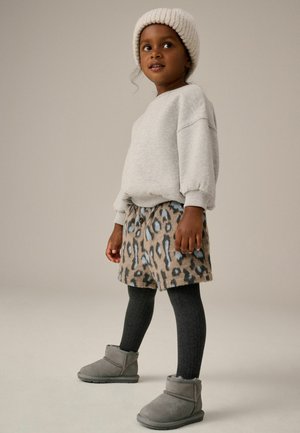 Grauer Baumwoll-Sweatshirt, Rock mit beige-blauem Leopardenmuster, dunkelgraue Leggings und graue Stiefeletten mit weicher Textur. Strickmütze in Creme.