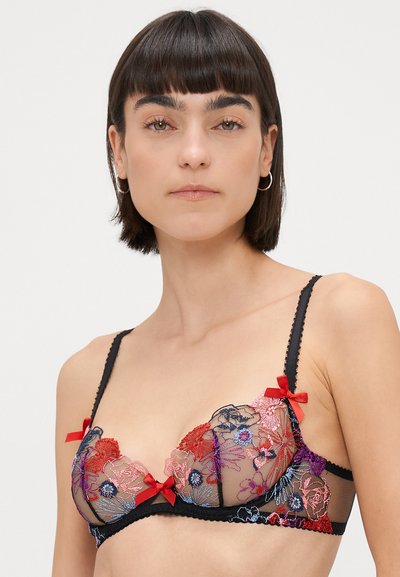 Sostenedor de encaje negro con bordado floral en rojo, rosa y azul. Presenta acentos de cinta roja y tirantes ajustables con bordes festoneados.