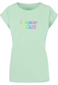 Lysegrøn t-shirt med korte, rullede ærmer og en rund halsudskæring. Forsiden har multicoloreret tekst "Summer & Chill" i en legesyg skrifttype.