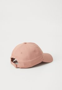Baseball cap in soft pink fabric, featuring a rounded crown, curved brim, and adjustable strap at the back. Solid color, no patterns.