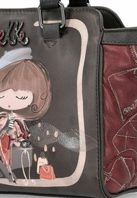 Borsa in pelle grigia con un accento bordeaux. Presenta un'illustrazione giocosa e un logo metallico. Texture liscia con dettagli di cucitura visibili.