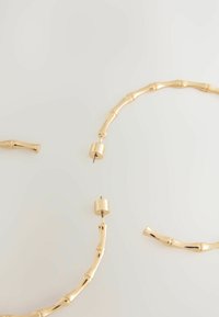 Cercei din aur cu un design asemănător bamboosului, având o textură netedă și lustruită și închizători cilindrice la capete.