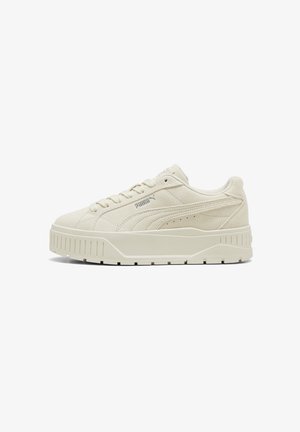 Baskets Puma en daim blanc cassé avec une semelle épaisse texturée, lacets à l’avant et marquage discret sur le côté et la languette.