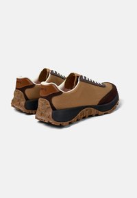 Sneaker marroni e beige con una tomaia testurizzata, suola in gomma e lacci bianchi. Presenta dettagli marroni scuri e una suola leggermente elevata.