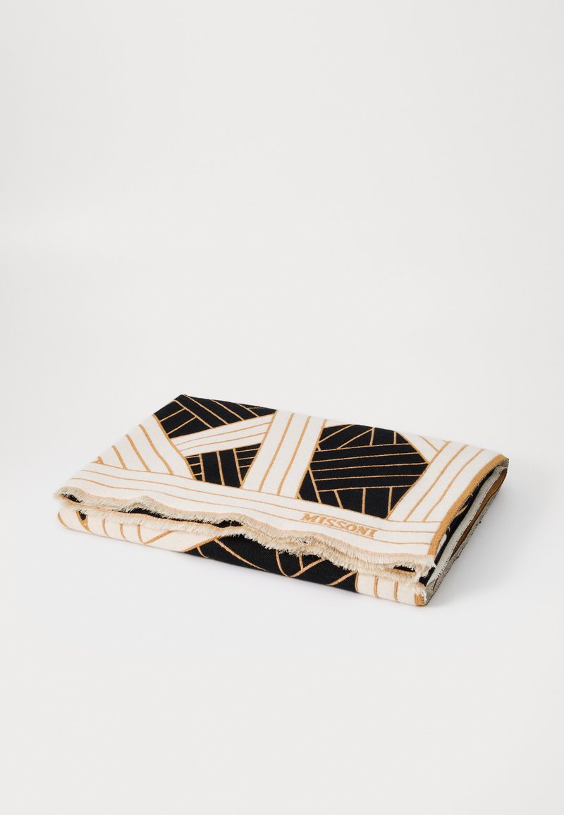 Wpleciony koc z geometrycznym wzorem w czerni i kremie, z złotymi akcentami; frędzle na krawędziach; oznakowany napisem "MISSONI."