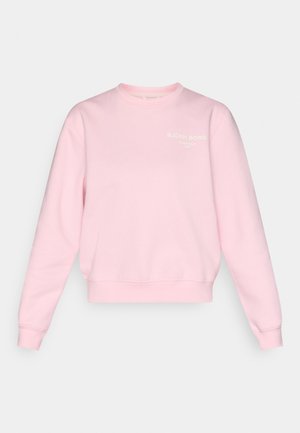 Ανοιχτό ροζ φούτερ φτιαγμένο από απαλό ύφασμα. Διαθέτει στρογγυλή λαιμόκοψη, μανίκια με μανσέτα και λευκό λογότυπο στο μπροστινό αριστερό μέρος.