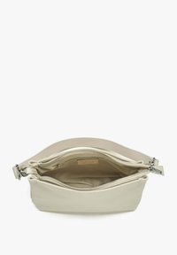 Jasnobeżowa skórzana torba o gładkiej teksturze, z podwójnym zapięciem na zamek i przestronnym wnętrzem z metką logo w środku.