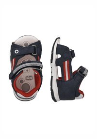 Sandali blu e rossi con cinturini regolabili, soletta imbottita e suola in gomma bianca. Presentano un design a ritaglio e due strisce rosse.