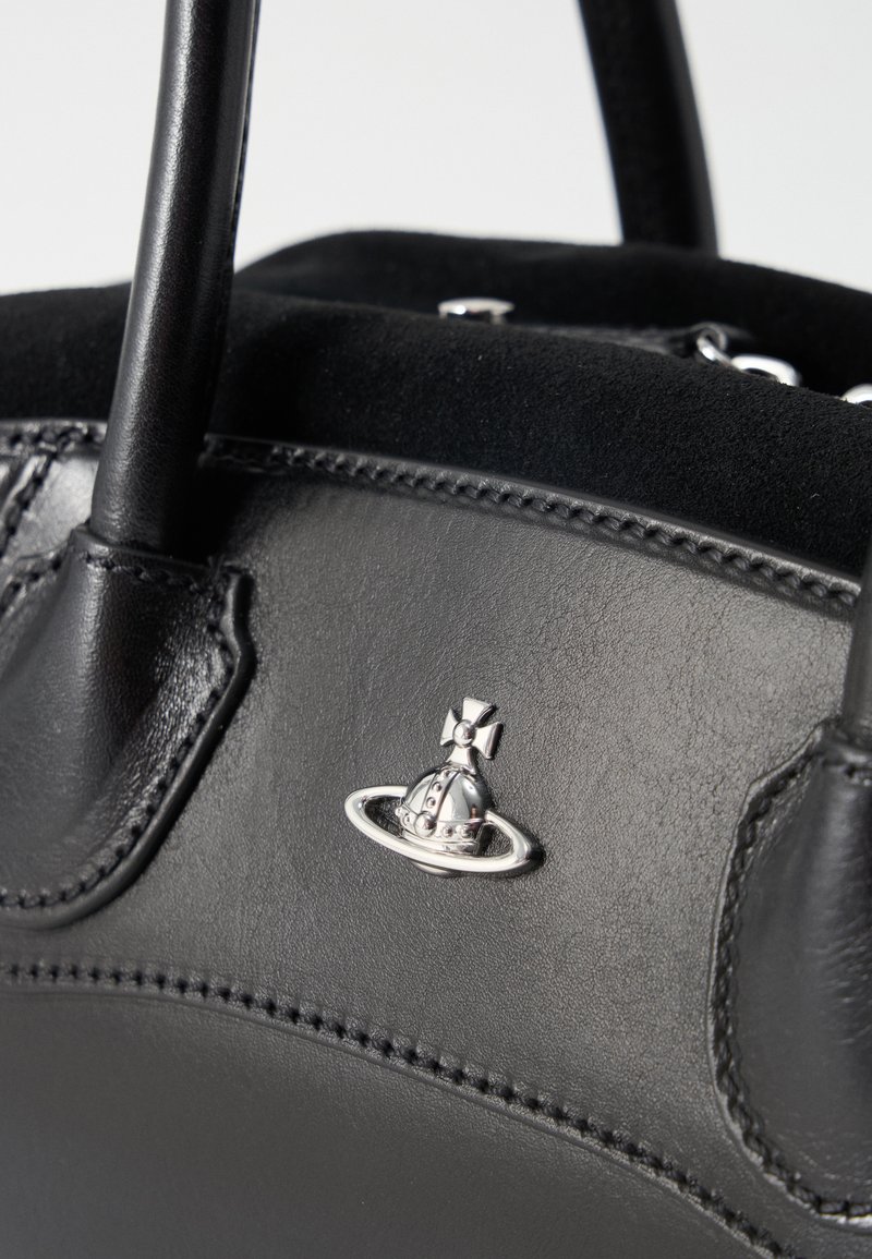 Black leather handbag with dual handles and a small silver Saturn-shaped metal emblem on the front panel.
