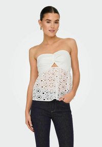 Top bianco senza spalle con un fiocco frontale, caratterizzato da un tessuto testurizzato e una parte inferiore ricamata con pizzo con motivi floreali.