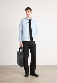 Hele sinine nööpideta jakk mustade nööpidega, kantud musta kampsuni peal, koos mustade pükstega ja musta käsitootud kotiga. Sujuv siidine tekstuur.