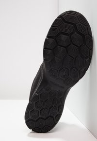 Black athletic shoe sole featuring a hexagonal pattern, made of rubber. Upper textured mesh material, angled against a white background.