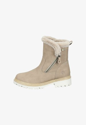 Beige ankle boots made of suede with a faux fur lining, featuring a side zipper, thick white rubber sole, and stitched detailing around the base.