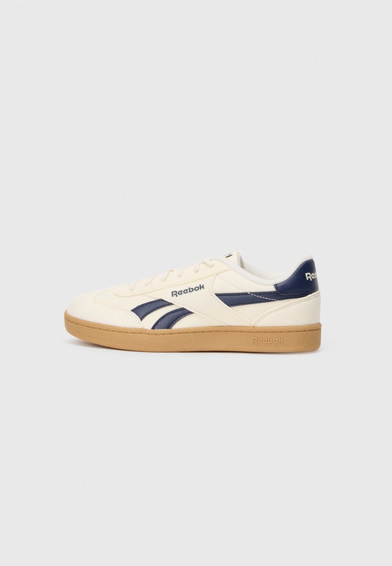 Reebok sporta apavi ar krēmveida ādas virsu, zila akcenta detaļām, apaļu purngali un gumijas zoli. Tekstūrēta dizaina ar svītru detaļu.