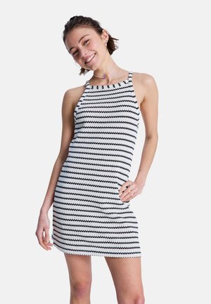 Schwarz-weiß gestreiftes Kleid mit Neckholder-Ausschnitt, figurbetontem Design und strukturiertem Strickmaterial. Kurze Länge mit dezentem wellenförmigem Muster.
