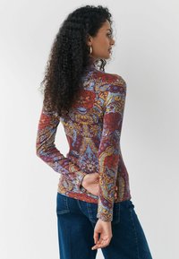Bluză cu mânecă lungă, decorată cu un imprimeu floral și paisley colorat în nuanțe de roșu, albastru și galben, realizată dintr-un material texturat cu elasticitate.
