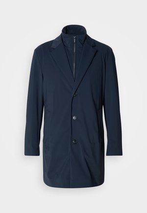 Mornarska duža jakna izrađena od glatkog materijala, s izrezanim ovratnikom, prednjim gumbima i bočnim džepovima; moderna, krojena izvedba.