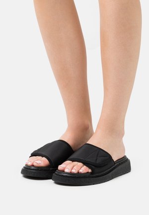 Sandales noires à glissière avec une tige en textile matelassé, bout ouvert et semelle extérieure en caoutchouc texturé ; design léger et décontracté.